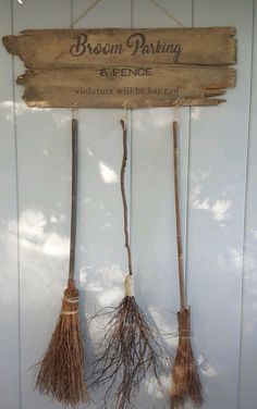 three brooms hanging from a wooden sign that says broom parking