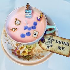 there is a cup cake on the plate with some charms and a drink bottle next to it