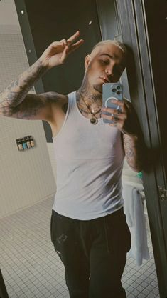 a man with tattoos taking a selfie in the mirror while holding a cell phone