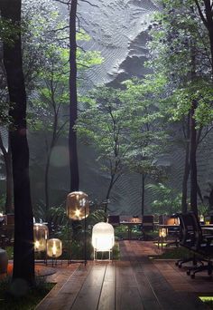 an outdoor area with tables, chairs and lights in the middle of it surrounded by trees