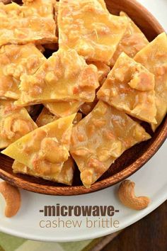 a wooden bowl filled with pieces of cake next to cashews