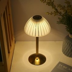 a table lamp sitting on top of a white counter next to a vase with flowers