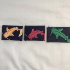 four different colored fish painted on black tile blocks in the shape of squares, each with an individual's own name