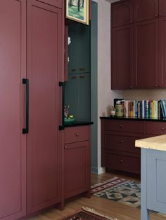 a kitchen with red cabinets and an area rug on the floor in front of it