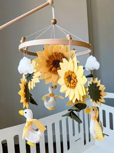 a crib mobile with sunflowers and ducks hanging from it