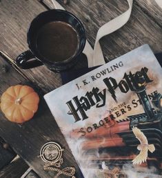 a harry potter book sitting on top of a wooden table next to a cup of coffee