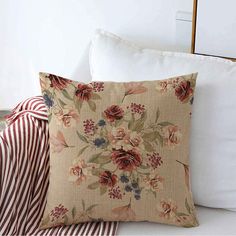 a close up of a pillow on a bed with pillows in the foreground and a striped blanket behind it