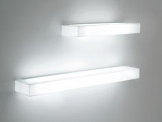 two white shelves with lights on them against a wall