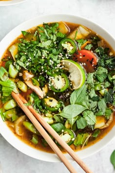 a white bowl filled with vegetable soup and chopsticks