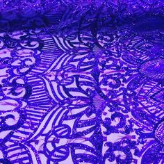 purple sequins and beads are displayed on a tablecloth that has been made into an intricate pattern