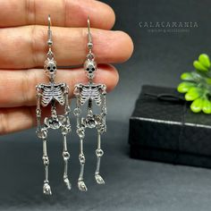 Get ready to dance the night away with these one-sided skeleton earrings in a vintage metallic silver finish! Perfect for any occasion - Halloween, Day of the Dead, a birthday party, or a night out with friends. Lightweight, articulated (all limbs are movable) and beautifully detailed, these earrings make a unique and original gift for yourself or someone special. Add some gothic, punk, and tattoo fashion to your look with these playful and quirky CALACAMANIA™ accessories Earrings details: Size: Edgy Halloween Jewelry For Costume Party, Punk Style Hand Cast Halloween Jewelry, Bone Colored Metal Earrings For Pierced Ears, Silver Metal Jewelry For Costume Party, Punk Skull Earrings For Party, Sterling Silver Jewelry For Halloween Party, Metal Halloween Party Jewelry, Edgy Skull Earrings For Parties, Gothic Skull Earrings For Party