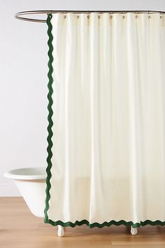 a white shower curtain with green scalloped trim on the edge and bottom in front of a bathtub