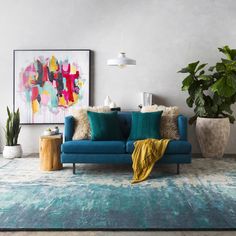 a living room with a blue couch and potted plants on the side table in front of it