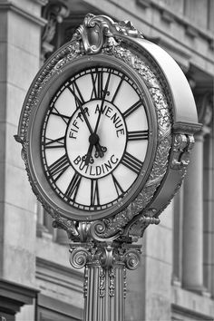 a large clock with roman numerals stands in front of a building