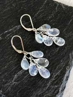 Rainbow Moonstone Earrings, White Cluster Earrings in Gold or Silver, Teardrop Statement Earrings, June Birthstone Jewelry Gift for women These luminous white cluster earrings feature blue flash rainbow moonstone teardrops wire wrapped to an oval chain forming a short cluster. These white statement earrings are perfect for summer and matching with virtually everything in your closet, they have lots of blue flash so they reflect colors from within. These will turn heads anywhere you go. About The White Statement Earrings, Watermelon Tourmaline Necklace, Tiny Heart Necklace, June Birthstone Jewelry, Rose Quartz Heart, Tourmaline Necklace, Moonstone Earrings, June Birthstone, Earrings In Gold