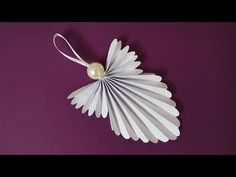 a paper fan with a pearl hanging from it on a purple wall next to a white string