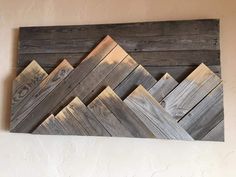 a wooden wall hanging on the side of a building with wood planks in it