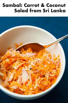 a white bowl filled with shredded carrots on top of a blue table next to a spoon