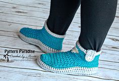 a woman's feet wearing blue crocheted slippers on top of a wooden floor