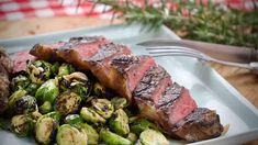 steak and brussel sprouts are served on a plate with a fork