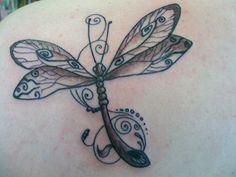 a dragonfly tattoo on the back of a woman's shoulder