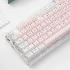 a pink and white computer keyboard sitting on top of a desk next to a mouse