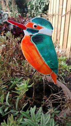 a glass bird sitting on top of a plant