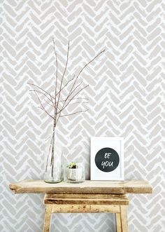 a wooden table topped with a vase filled with flowers next to a wallpapered wall