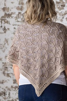 a woman wearing a beige knitted shawl with an openwork design on the back