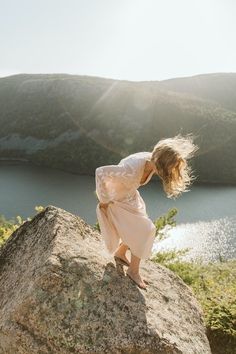 a woman standing on top of a large rock