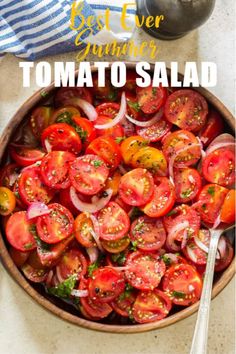 a wooden bowl filled with sliced tomatoes and onions next to a silver serving utensil