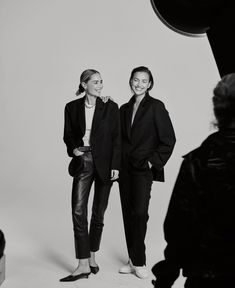 two women standing next to each other in front of a camera