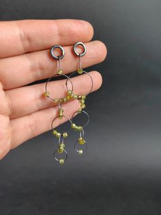 This listing is for a super delicate pair of earrings. Hanging from a handmade sterling silver stud, the light hammered links and  these beautiful faceted pieces olive green Cubic Zirconia, the cut makes them shine so much, and they have a light change in hues! Each of the links has been formed by hand and then hammered, this light hammering hardens and makes the links keep their shape, the beads are free to move around making for a very attractive pair of earrings :) They are 7.2cms long. Made using sterling silver, darkened then polished for a shiny dark finish that makes the beads really pop. Matching chain and other earrings with different beads  available: https://www.etsy.com/shop/Nataliaraya Thank you for taking the time to read this! ------------------------------------------------ Kinetic Earrings, Earrings Hanging, Artisan Jewelry Handmade, Oxidized Silver, Sterling Silver Studs, Handmade Sterling Silver, Handmade Artisan, Stone Jewelry, Beaded Earrings