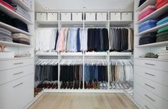 an organized closet with white drawers and shelves filled with folded shirts, pants and shoes