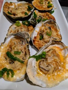 several oysters on a white plate with green garnishes and seasoning