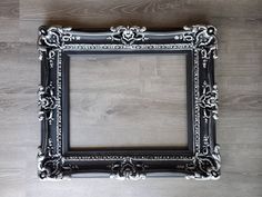 an ornate black and white frame on a wooden floor with wood floors in the background