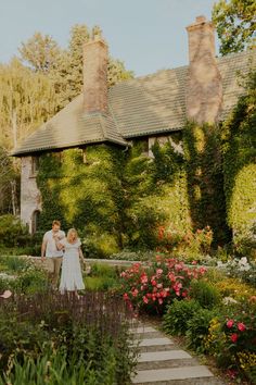 a bride and groom walking through the garden