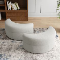 two white chairs sitting on top of a rug in front of a book shelf filled with books