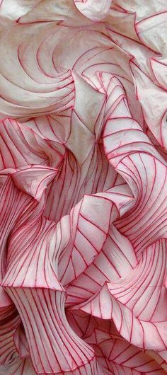 a close up view of pink and white swirled paper with red swirls on it