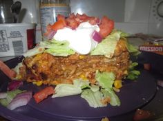 a purple plate topped with a taco and lettuce covered in sour cream