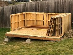 a wooden structure sitting in the grass next to a fence