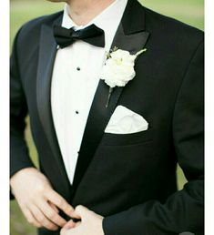 a man in a tuxedo with a white flower on his lapel collar