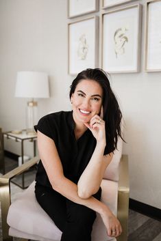 a woman sitting in a chair with her hand on her chin and smiling at the camera