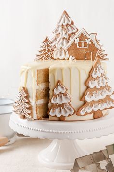 a cake with frosting and decorated trees on the top is sitting on a platter