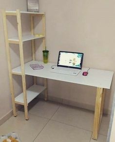 a laptop computer sitting on top of a white desk next to a wooden shelf filled with books