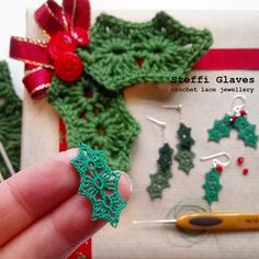 a hand is holding some crocheted christmas decorations and knitting needles in front of them