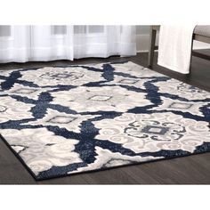 a blue and white area rug with an intricate design on the floor in front of a window