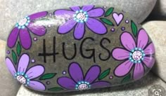 a rock with flowers painted on it that says hugs