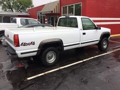 a white pick up truck parked in a parking lot next to a red brick building