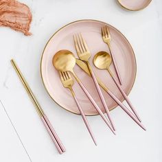 pink and gold place setting with utensils on white marble countertop, including two plates